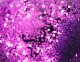 Texture abstraite de points violets lumineux se dissolvant dans un fond flou, creant une ambiance vibrante.