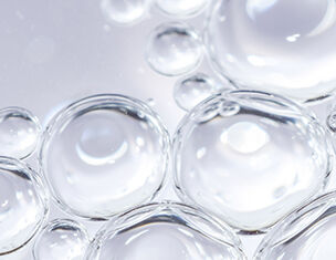 Gros plan sur des bulles d&aposeau transparentes flottant a la surface, creant une texture delicate et lumineuse.