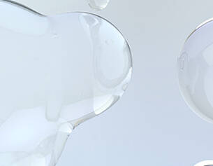 Gros plan sur des gouttes de liquide transparent sur fond clair, creant un effet de legerete et de fluidite.