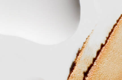 Abstract close-up of a textured surface featuring a smooth white background with a streak of brownish-orange paint or material on the right side.