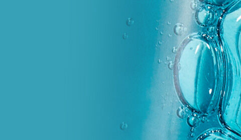 Close-up of a blue liquid with bubbles, set against a light background.