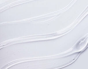 Swirls of creamy white texture on a smooth background, resembling skincare or cosmetic product application.