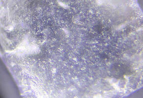 Close-up view of a translucent crystal, showcasing its surface texture and reflective properties under light.