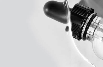 Close-up of a white medical device with a black dial and a transparent section, set against a light gray background.