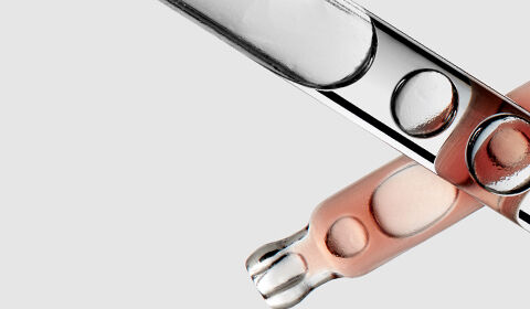 A close-up image of several test tubes, some filled with a peach-colored liquid, arranged against a light gray background.