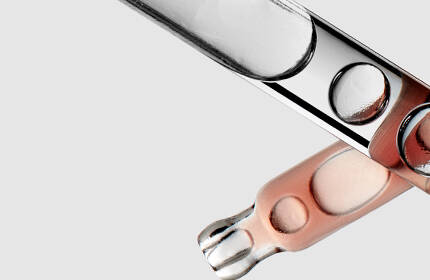 A close-up image of several test tubes, some filled with a peach-colored liquid, arranged against a light gray background.