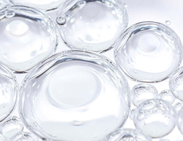Gros plan sur des bulles d'air transparentes a la surface d'un liquide clair, creant un effet de legerete et de fraicheur.