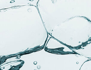 Gros plan sur des glacons transparents dans de l&aposeau claire, creant des bulles et des reflets lumineux.