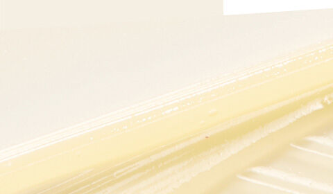 A close-up of a smooth, creamy spread on a light background, highlighting its texture and sheen.