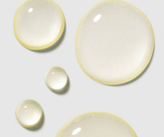 Drops of clear liquid in varying sizes, reflecting light against a soft gray background.