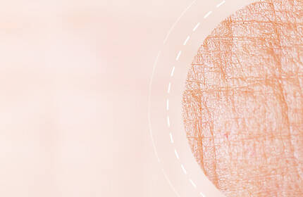 Abstract image featuring a soft, peach-colored background with a circular pattern that resembles textured skin.