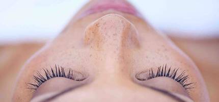 Een close-up van een vrouw met gesloten ogen, waarbij de focus ligt op haar wimpers en huid.