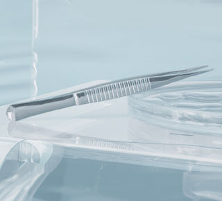 Close-up of a sleek dental instrument and a transparent dental tray, set against a soft blue background.