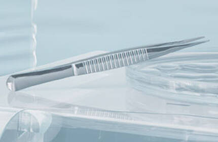 Close-up of a sleek dental instrument and a transparent dental tray, set against a soft blue background.