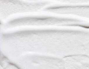 Close-up of smooth, white cream with soft, flowing texture and subtle ridges.