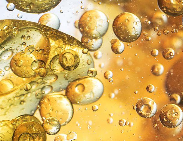 Close-up of golden bubbles and droplets suspended in a fluid, creating a mesmerizing abstract pattern.