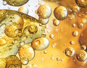Close-up of golden bubbles and droplets suspended in a fluid, creating a mesmerizing abstract pattern.