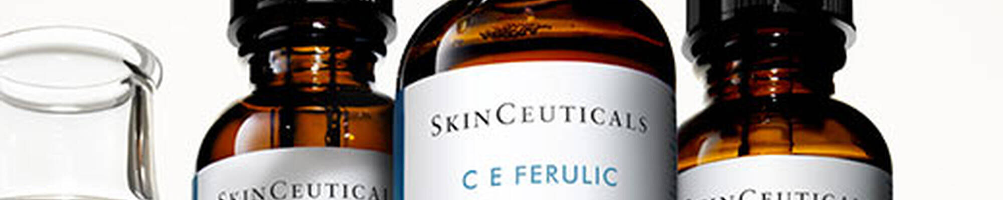 Trois flacons en verre de serum SkinCeuticals C E Ferulic avec une petite fiole a cote.