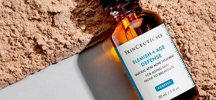 Flesje met serum voor huidverzorging op een achtergrond van lichtgekleurde poeder.