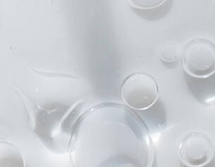 Gouttes d'eau et bulles sur une surface blanche, creant un effet de transparence et de legerete.