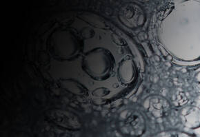 Close-up of water bubbles on a dark surface, showcasing their circular shapes and reflections.