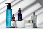 Verzorgingsproducten van Skinceuticals op een lichte achtergrond met schaduwen. Inclusief reiniger, serums en zonnebrandcreme.
